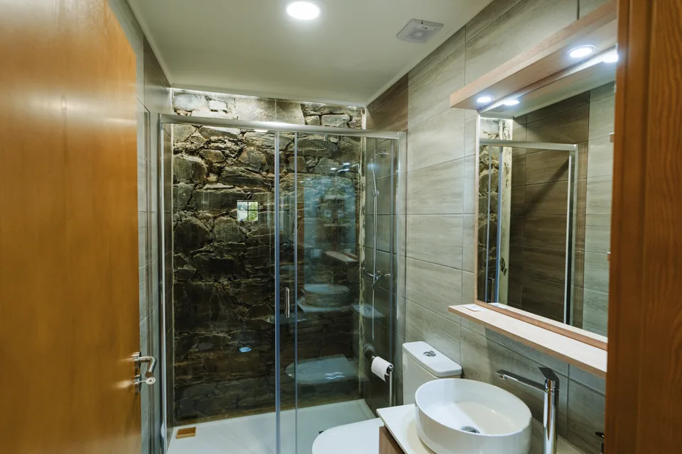 Suite bathroom, glass shower and visible stone wall