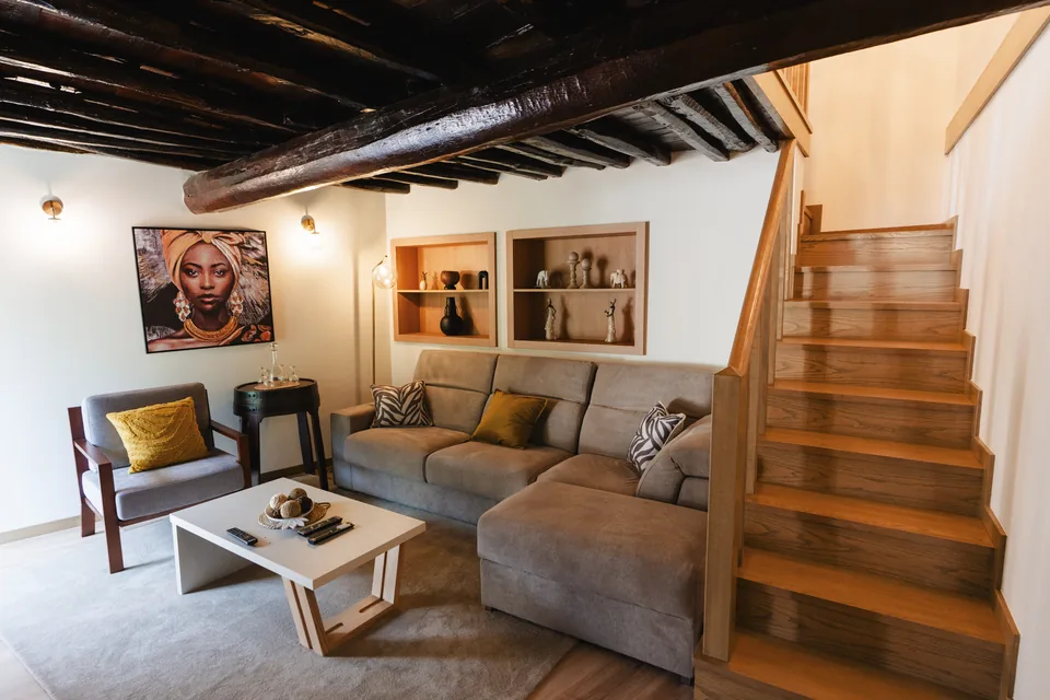 Sitting room with exposed ceiling beams, sofa and wooden stair