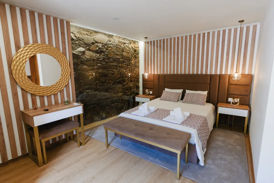 Suite double bed and mirror with exposed stone wall