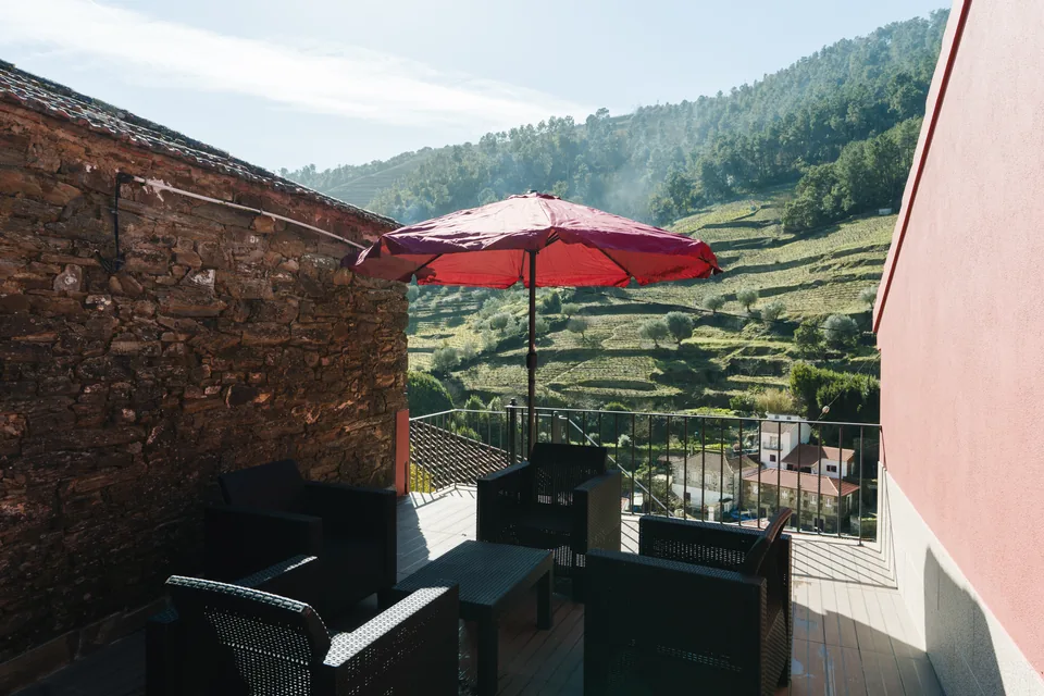 Furnished terrace, stone wall, red house facade and vineyard slopes